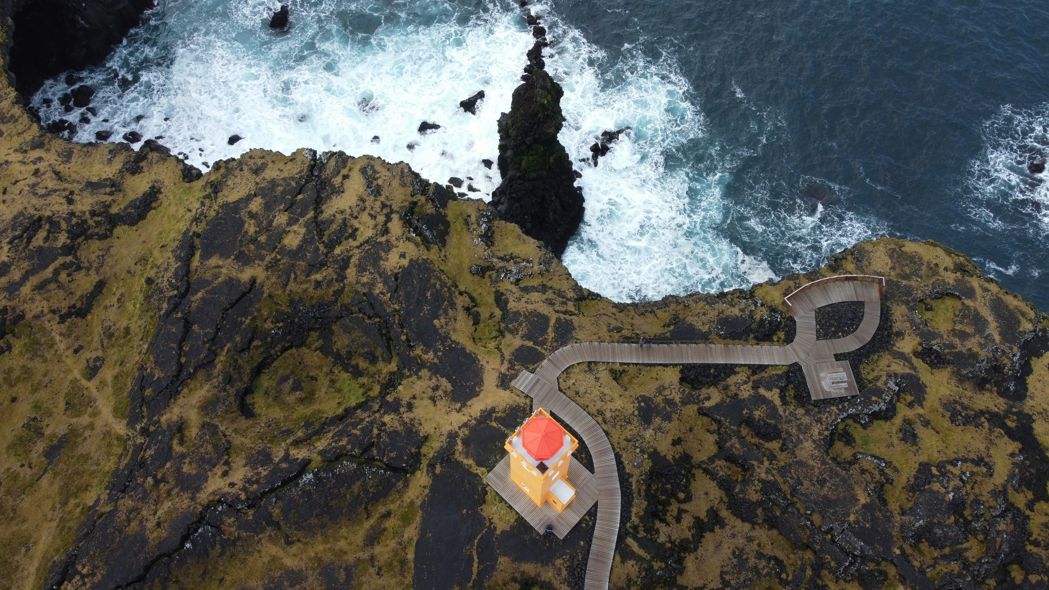 an aerial view of a lighthouse on a cliff by the ocean
