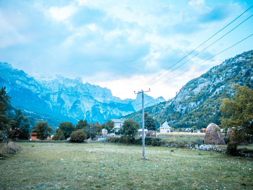 a field with a telephone pole and mountains in the background