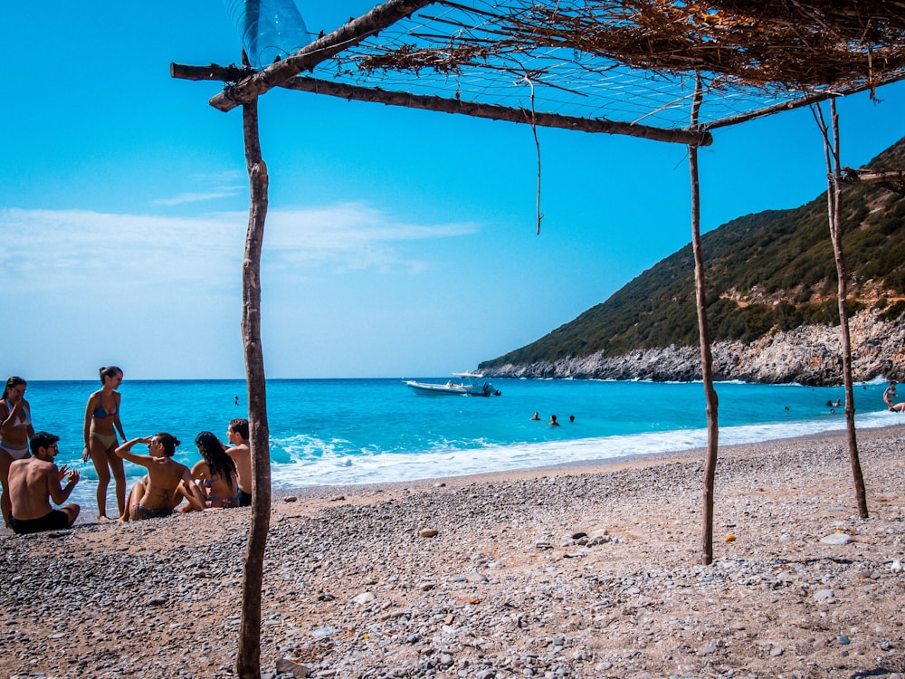 a group of people sitting on top of a sandy beach