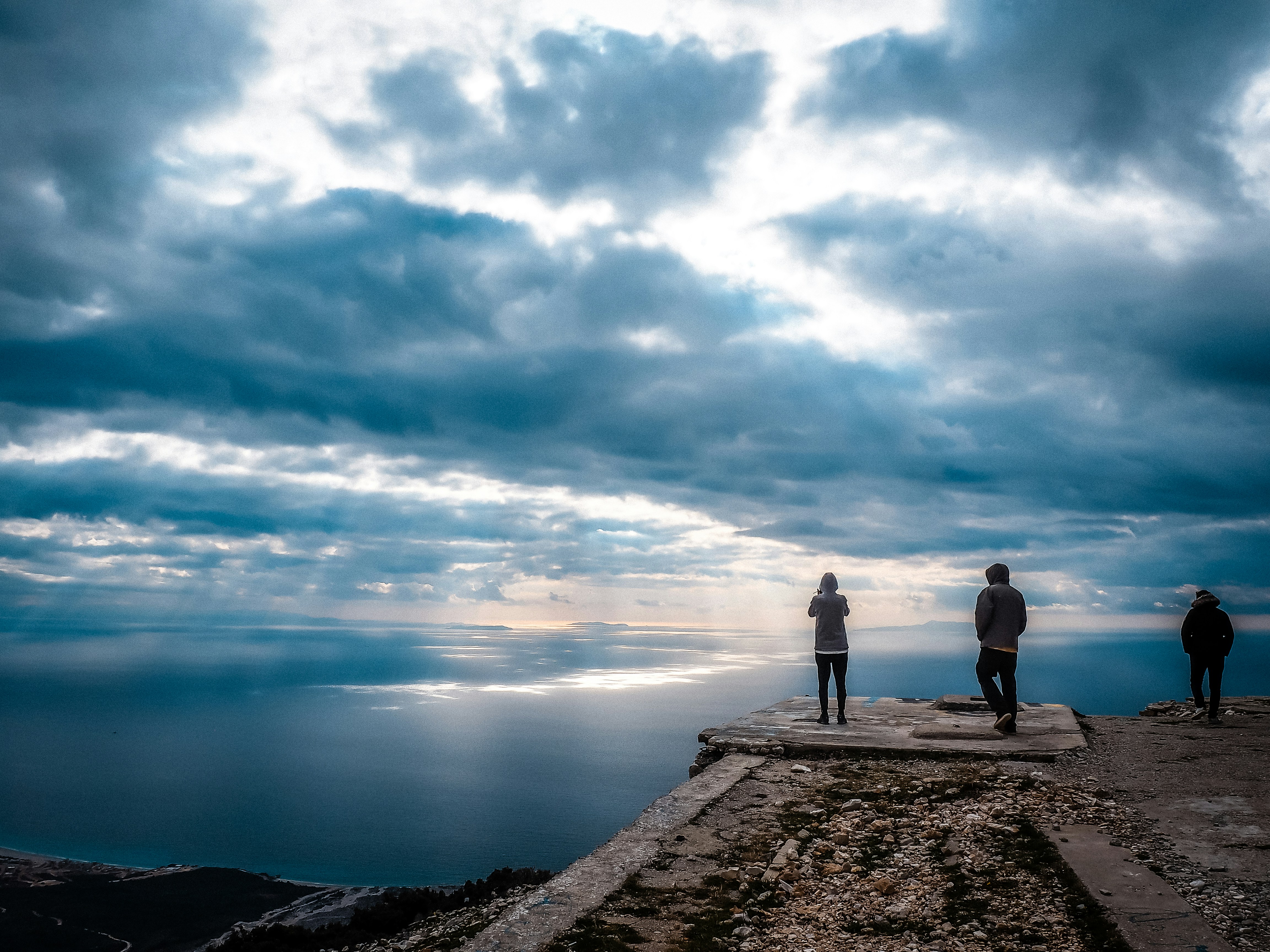 a couple of people standing on top of a cliff, 