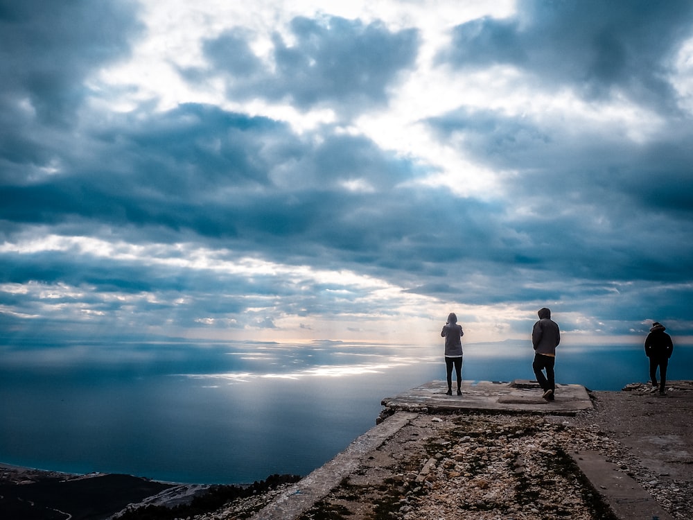 a couple of people standing on top of a cliff