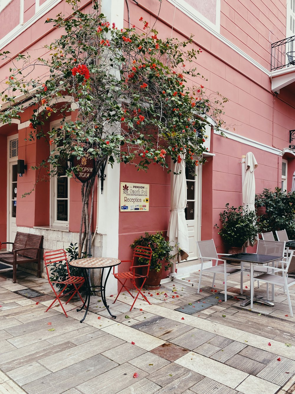 un bâtiment rose avec une table et des chaises à l’extérieur