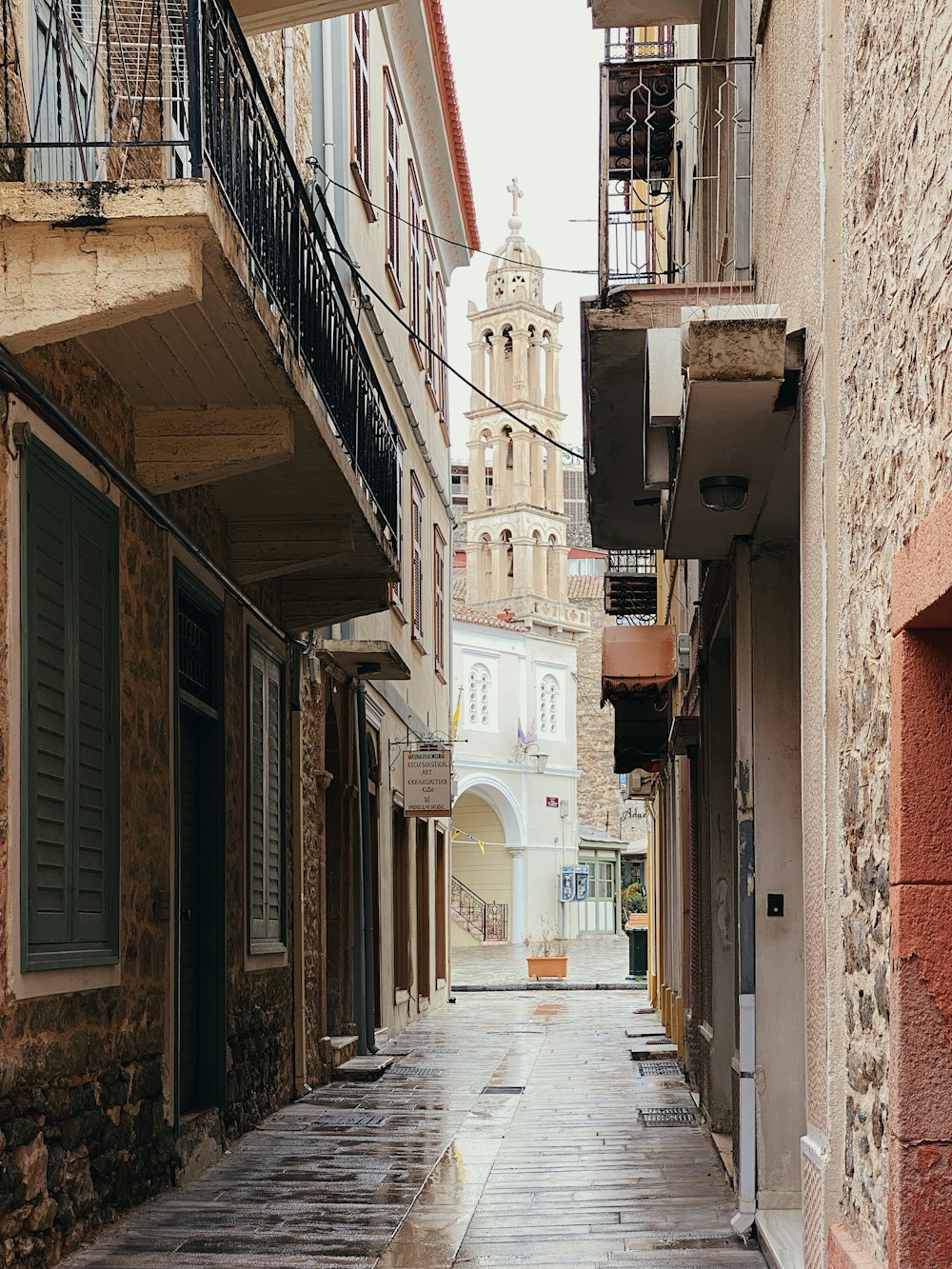 a narrow city street with a clock tower in the background