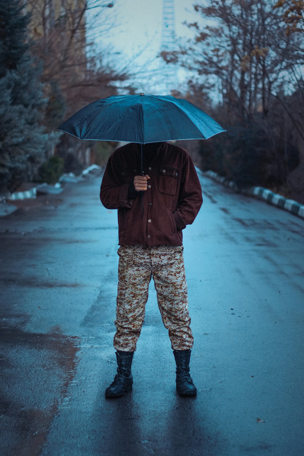 a man standing in the rain holding an umbrella