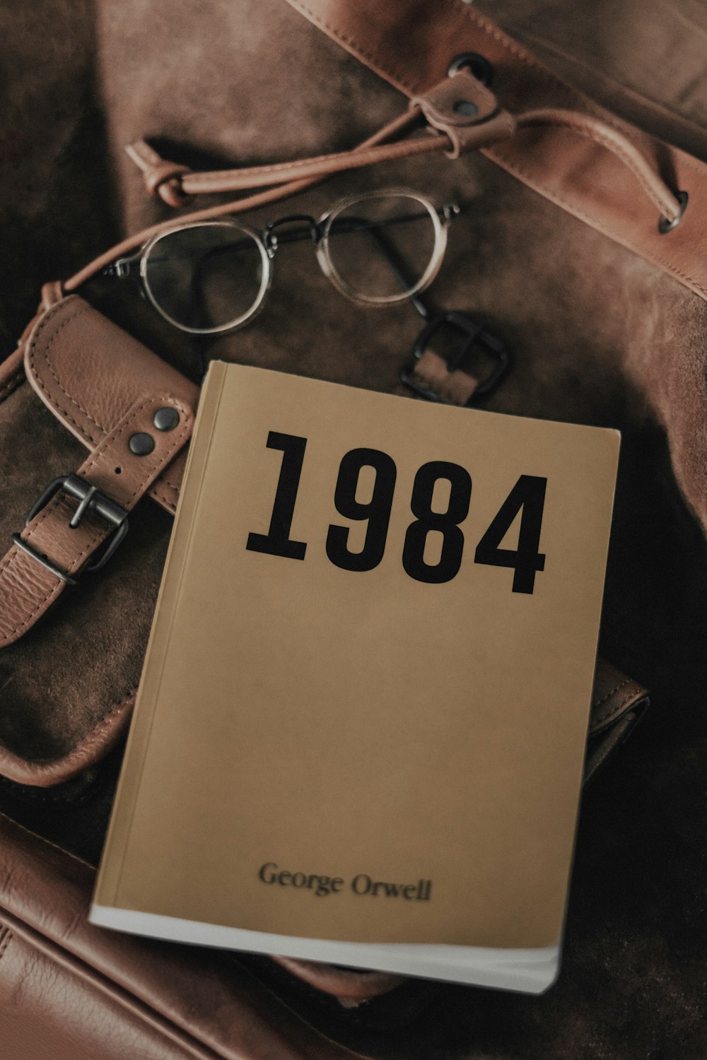 a book sitting on top of a bag next to a pair of glasses