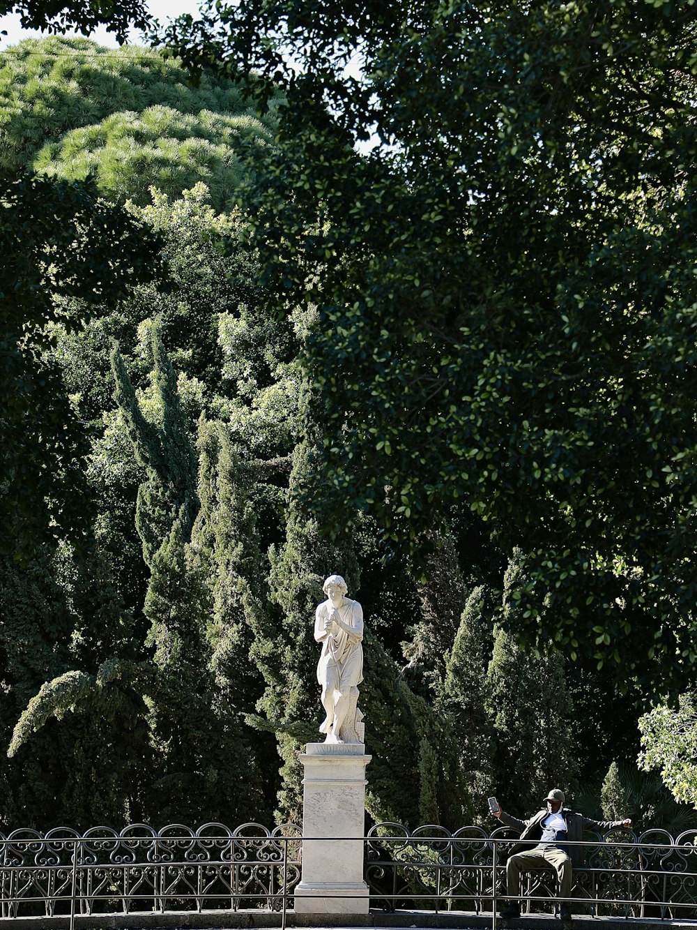 a statue in a park with trees in the background