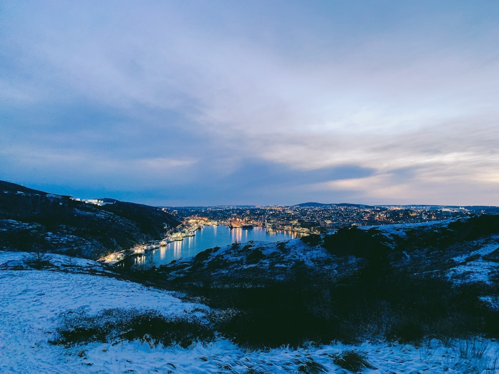 a snow covered hill with a body of water in the distance