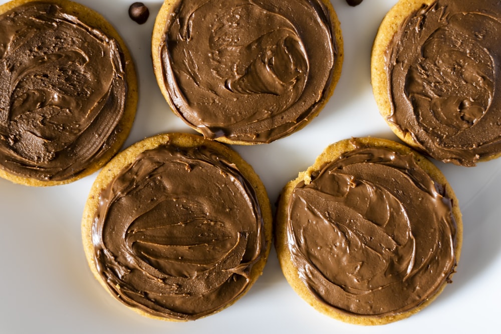 four cookies with chocolate frosting on a white plate