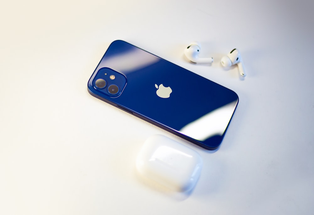 a blue iphone sitting next to a pair of ear buds