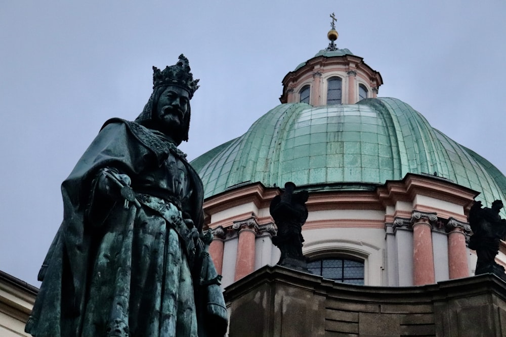 a statue stands in front of a domed building