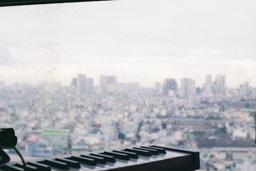 A vintage computer keyboard with a modern cityscape blurred in the background, symbolizing the intersection of technology and society.