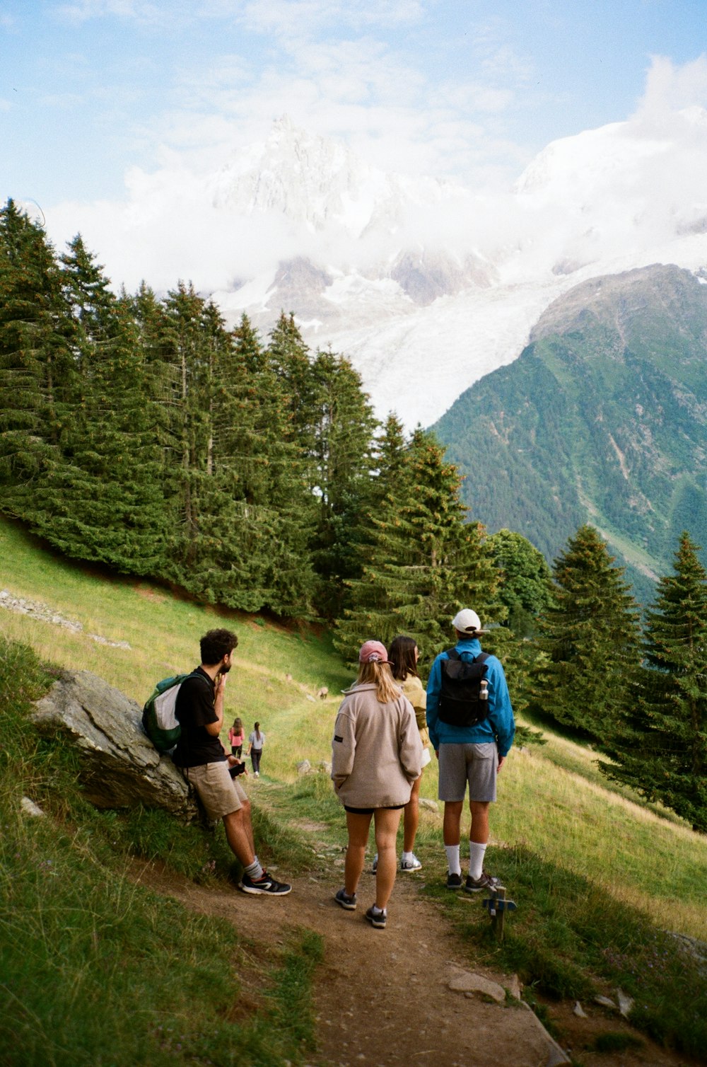 a group of people standing on top of a lush green hillside