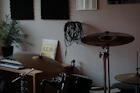 a drum set up in a room with a plant