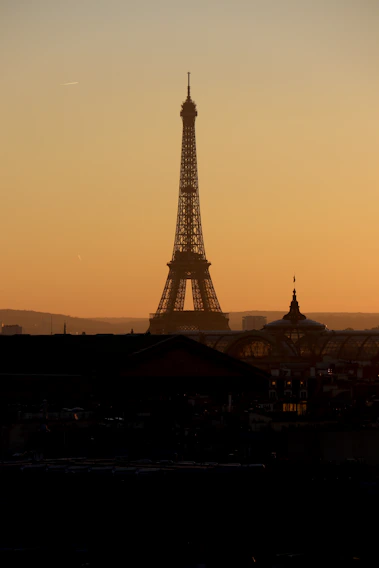 A vibrant photo of the Eiffel Tower glowing at sunset with a warm sky.