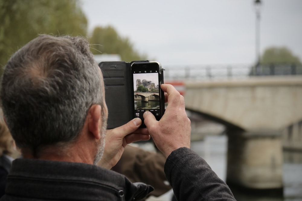 a man taking a picture of a bridge with his cell phone