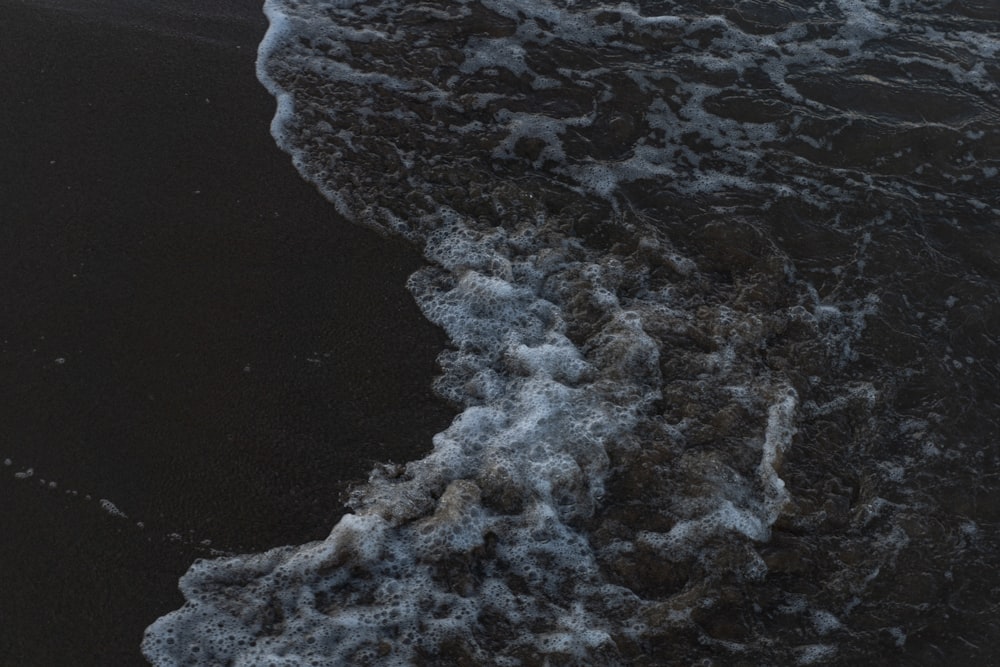 Ein schwarzer Sandstrand mit Wellen, die ans Ufer kommen