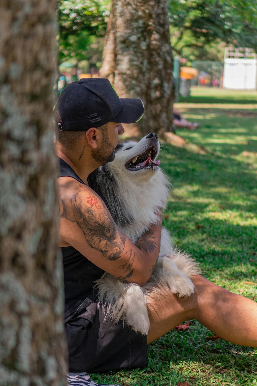 a man sitting on the ground holding a dog