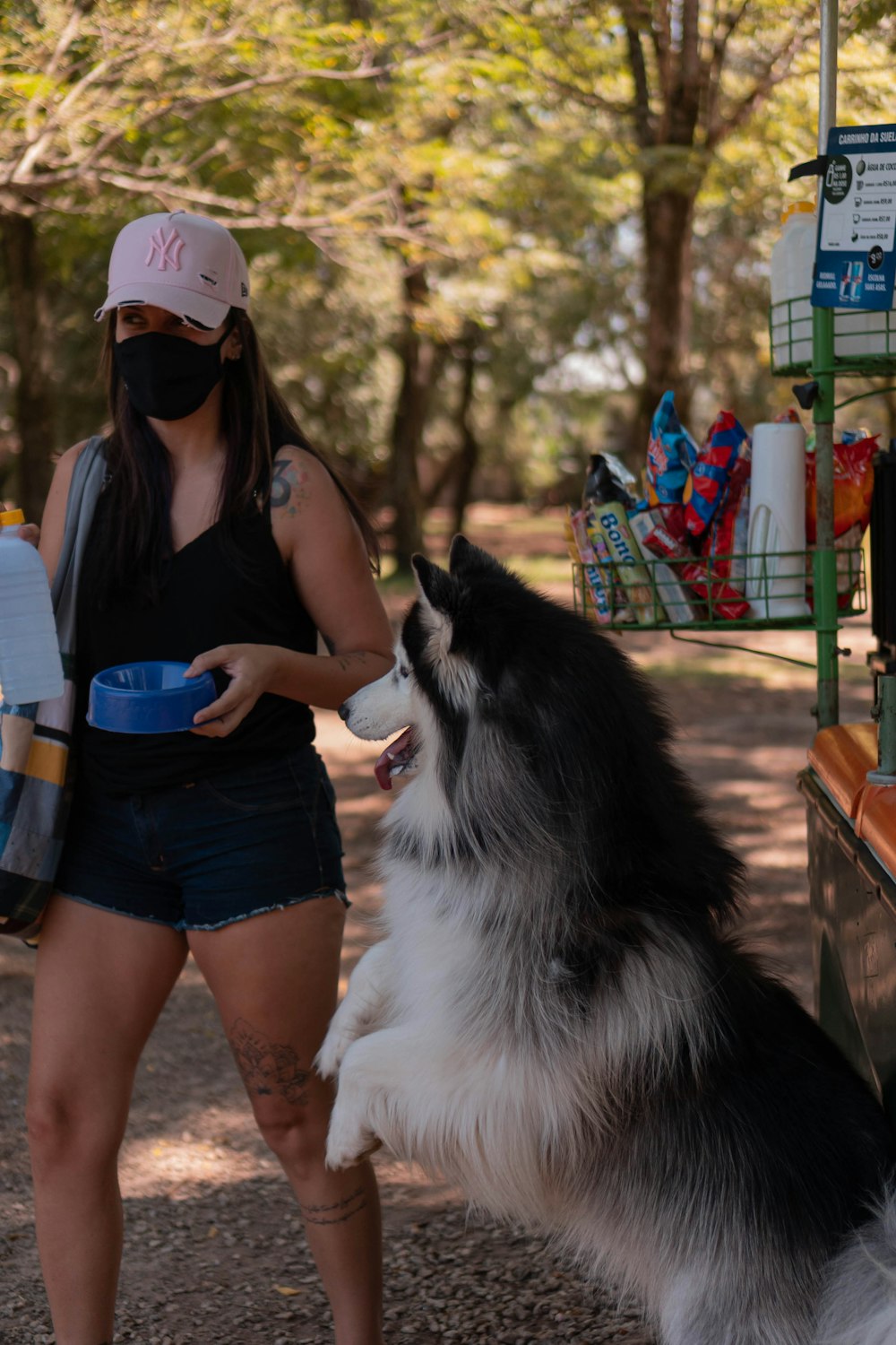 a woman wearing a face mask standing next to a dog