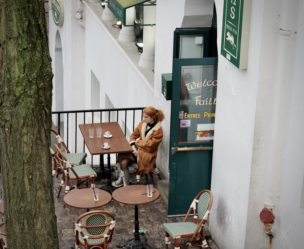 a person sitting at a table outside of a restaurant