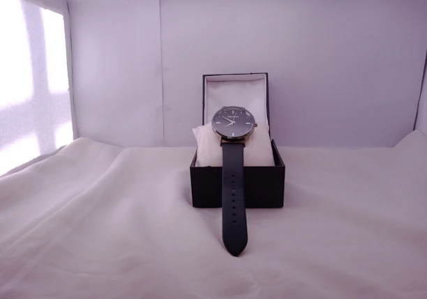 A close-up of a modern wristwatch displayed on a sleek black cushion.