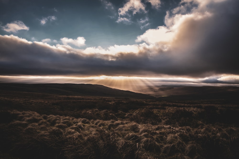 the sun is shining through the clouds over the hills