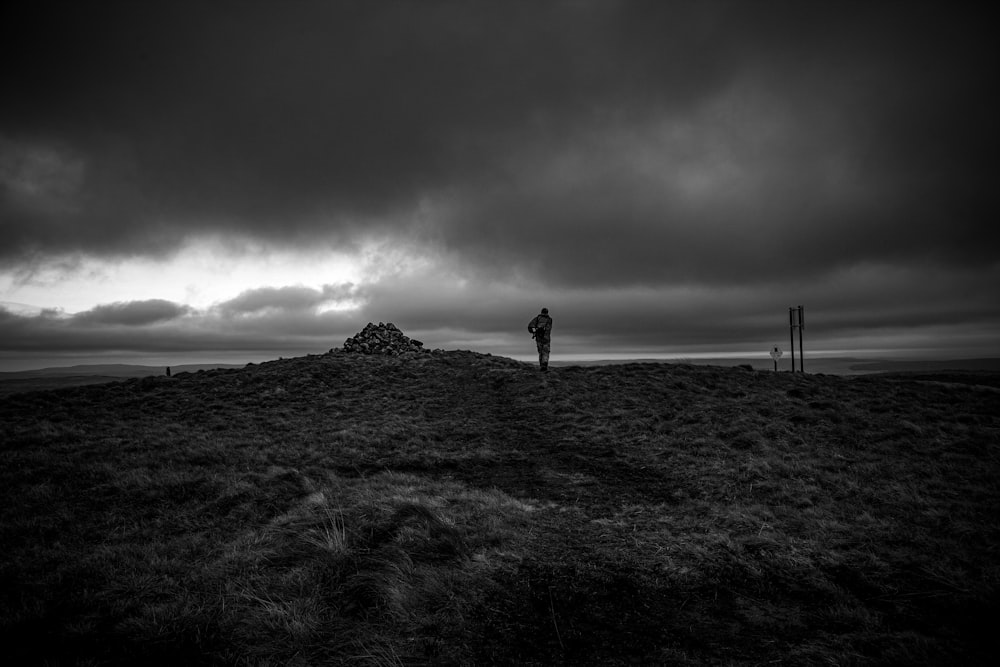a person standing on top of a hill under a cloudy sky