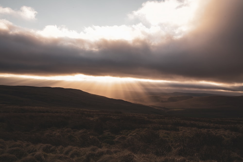 the sun is shining through the clouds over the hills