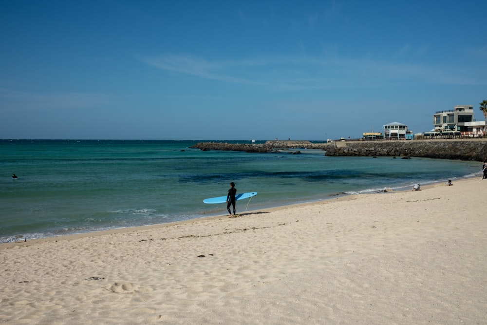 Una persona parada en una playa sosteniendo una tabla de surf