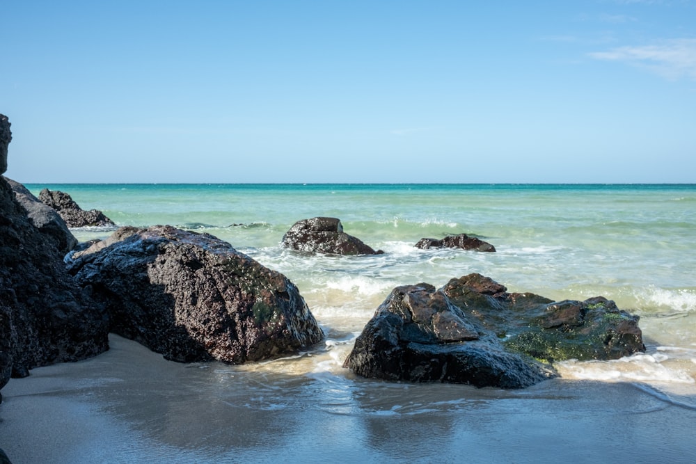 a beach with rocks and water on a sunny day