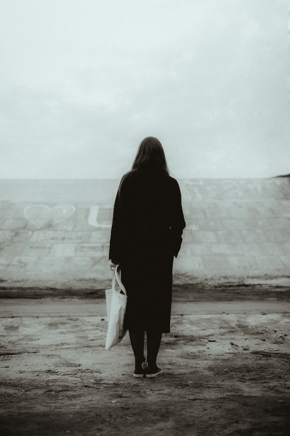 a woman in a black coat carrying a white bag