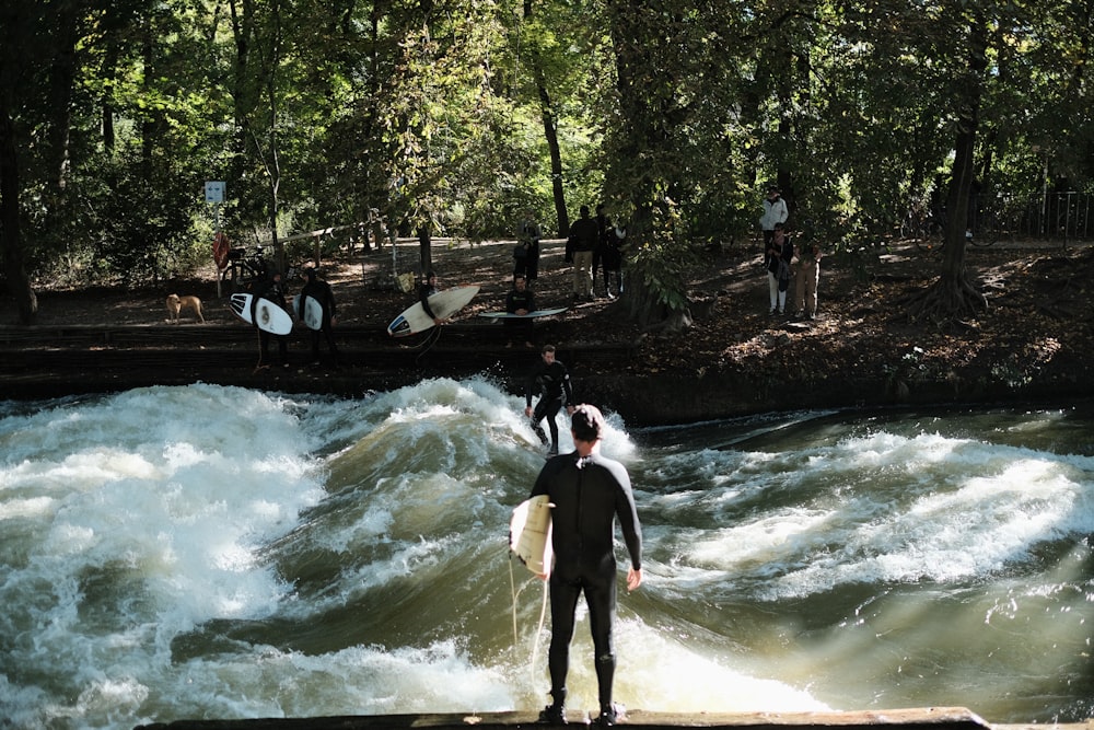 a man in a wet suit standing on a ledge above a river