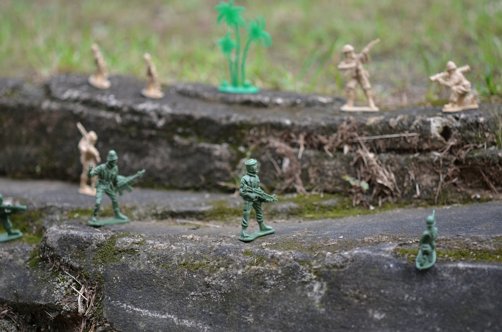 a group of toy army men standing on top of a rock