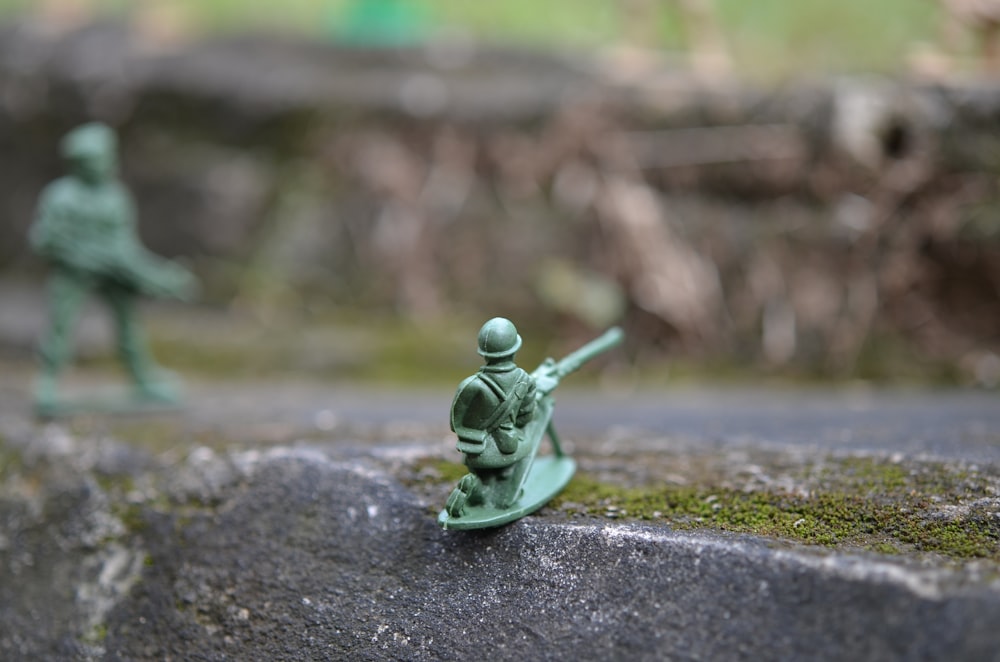 um soldado de brinquedo com uma arma em uma rocha