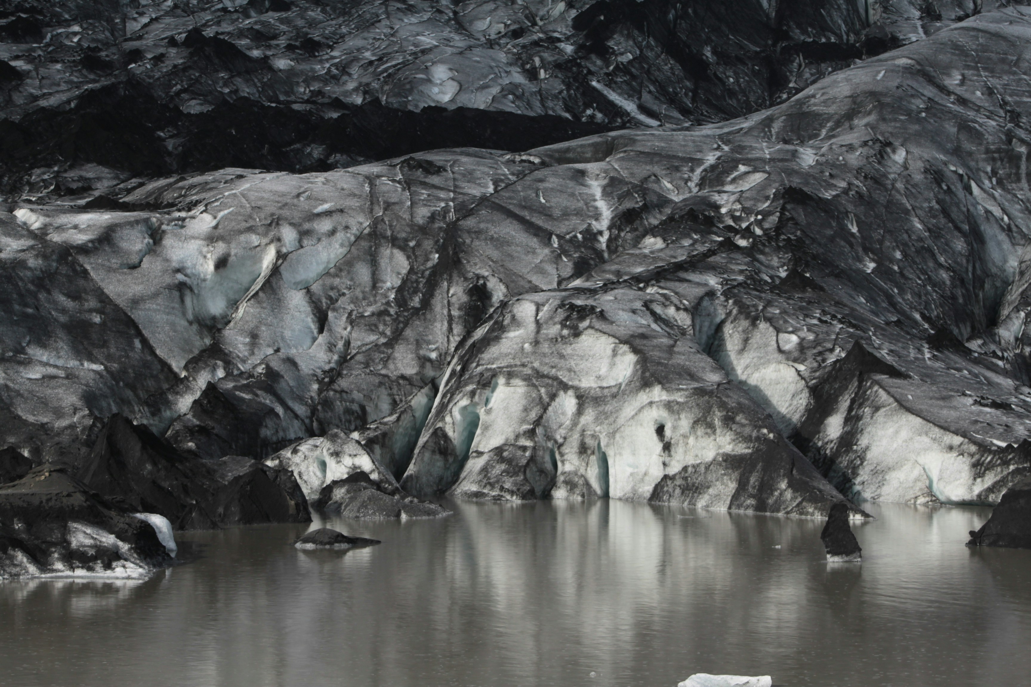 an iceberg floating on top of a lake surrounded by mountains