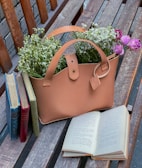 A vibrant Polar Totes bag resting on a sunlit wooden bench with fresh flowers peeking out.