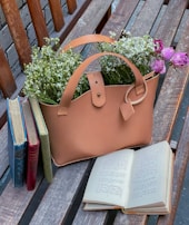 A vibrant tote bag resting on a wooden bench beside a sunlit window.