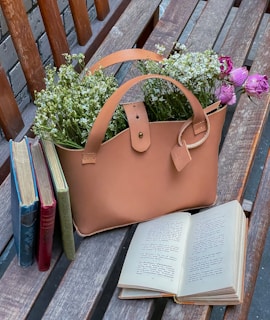 A stylish tote bag placed on a wooden table with flowers nearby.