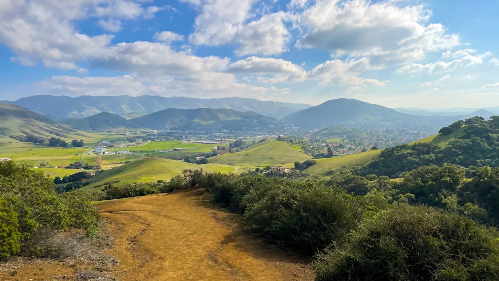 a dirt road going through a lush green valley