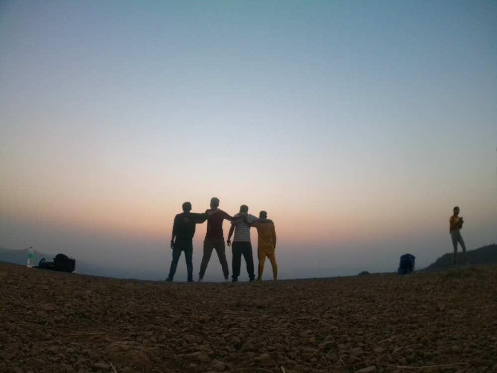 a group of people standing on top of a dirt field