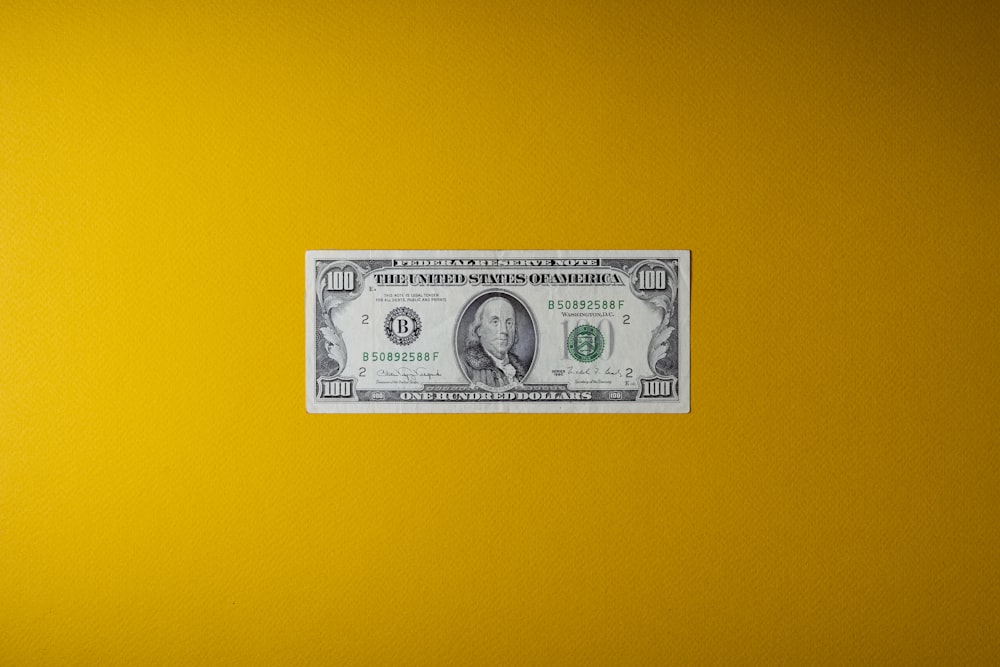 a one dollar bill sitting on top of a yellow wall