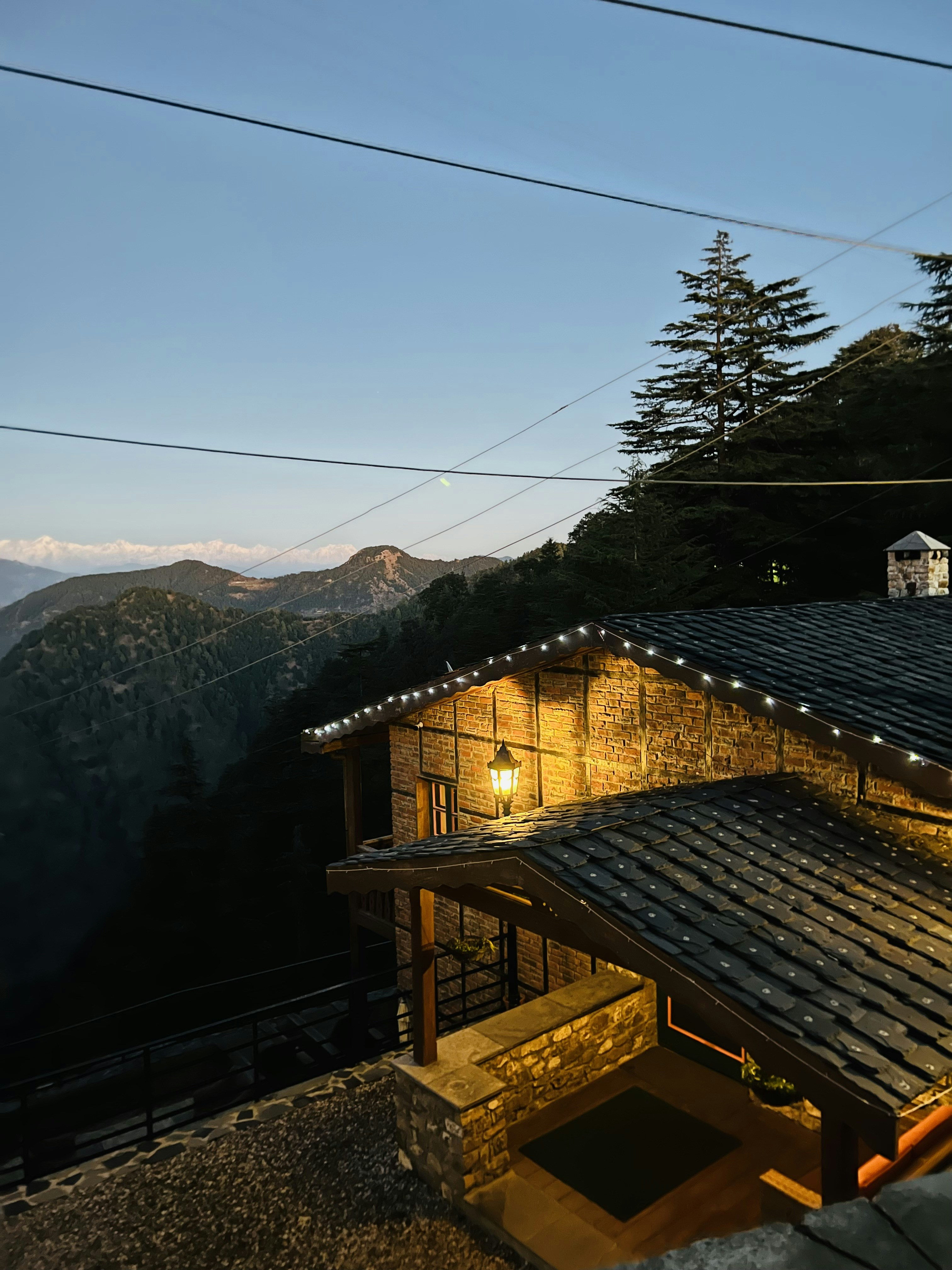 Rustic mountain lodge exterior with warm lighting at dusk surrounded by forest