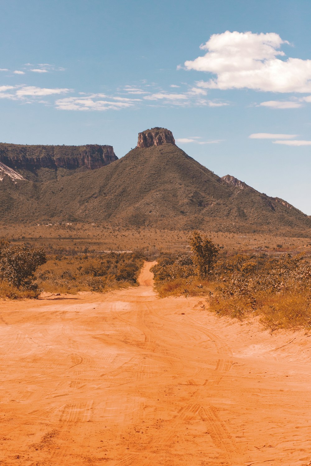 a dirt road with a mountain in the background