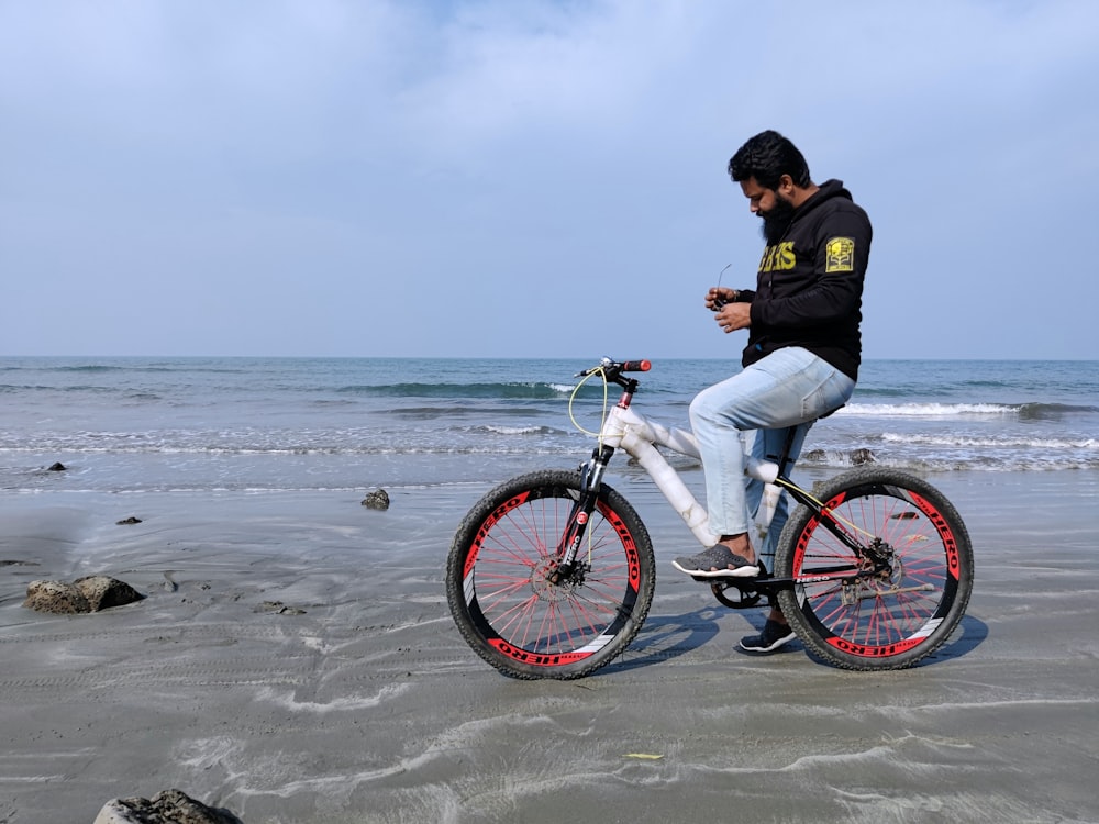 a man is sitting on a bike on the beach
