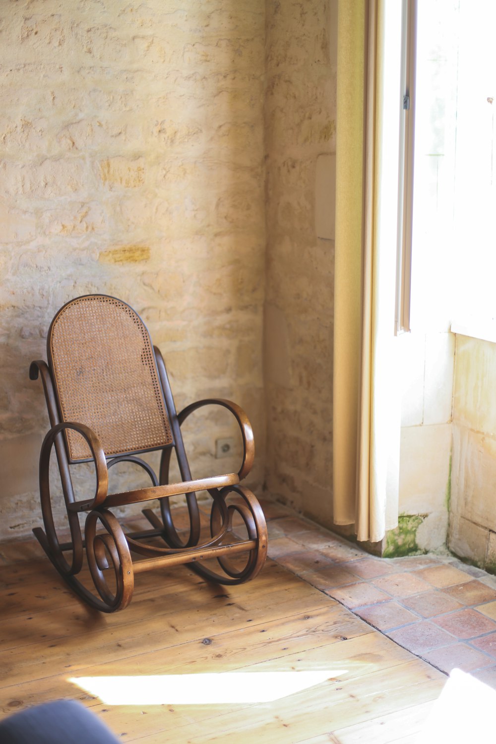 a rocking chair sitting in a room next to a window