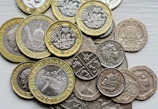 a pile of british coins sitting on top of a table