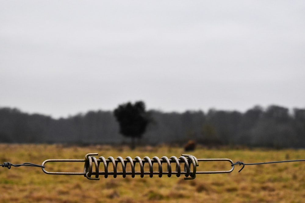 a wire fence in a field with a tree in the background