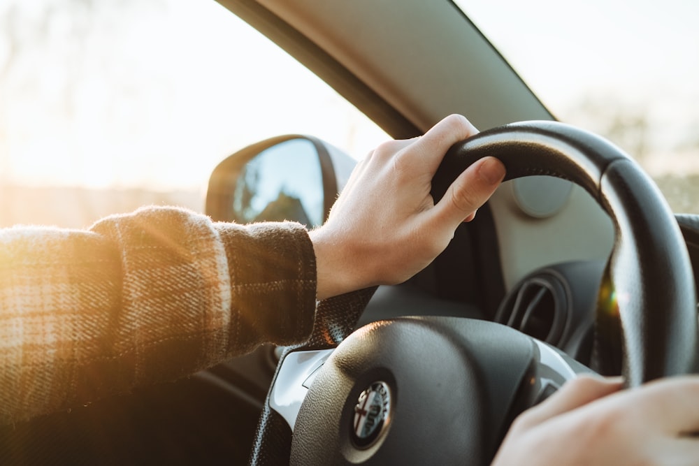 a person holding the steering wheel of a car