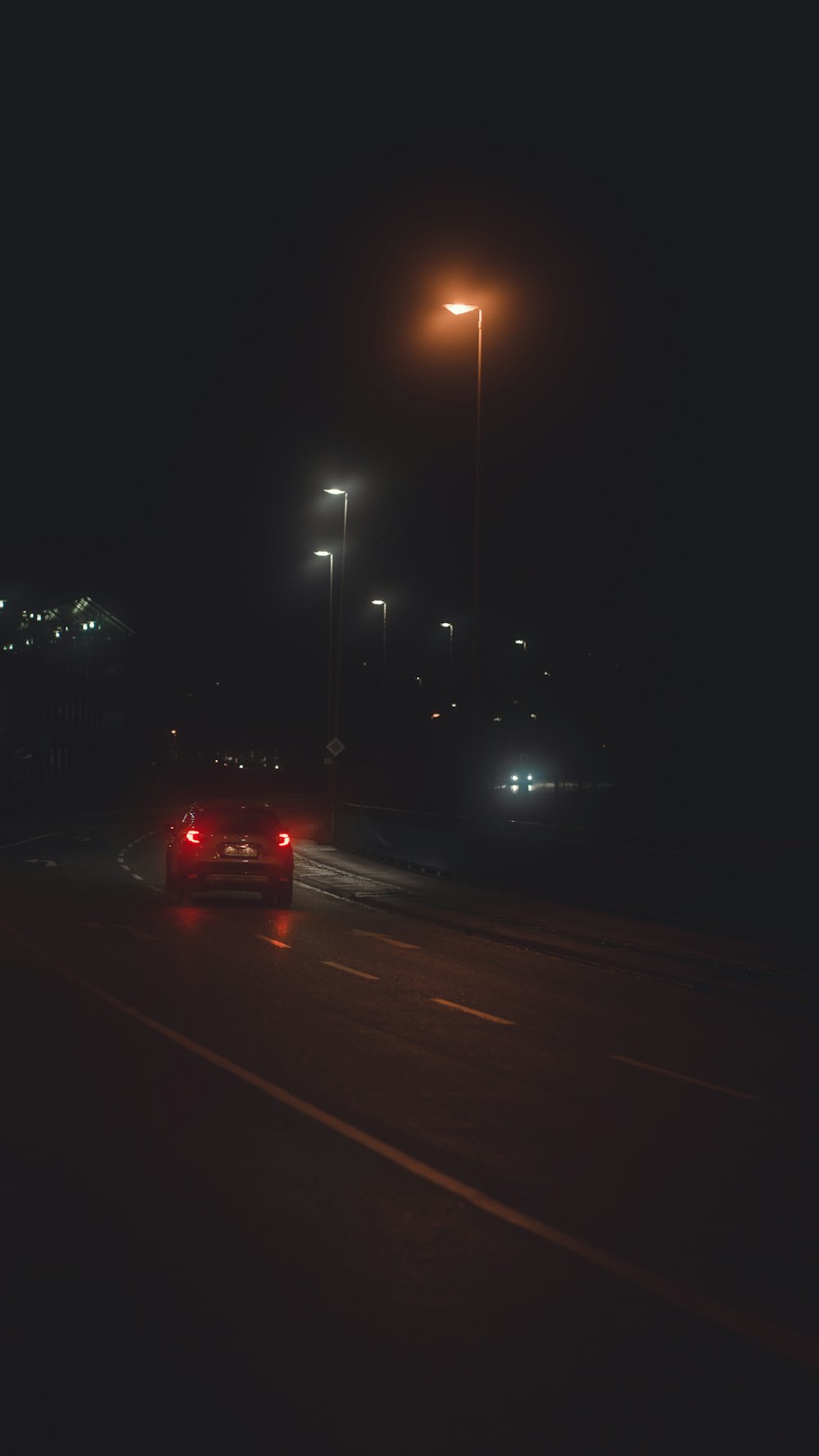 a couple of cars driving down a street at night