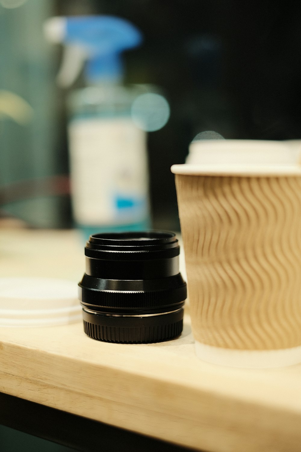 a coffee cup sitting on a counter next to a camera lens