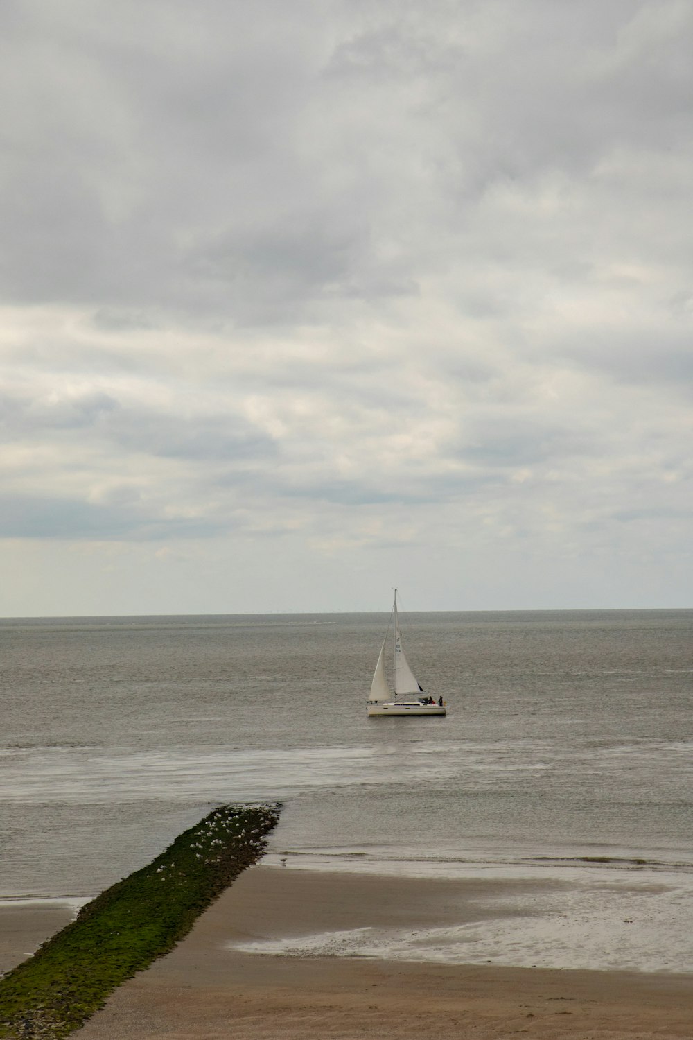 a sailboat in the ocean on a cloudy day